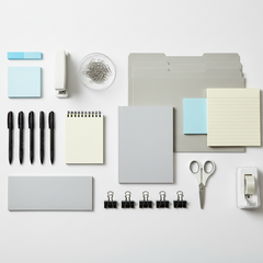 Assortment of general office supplies including pens, paper, and stapler on desk