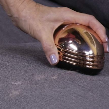 Portable mini desktop vacuum cleaner in gold color on a desk cleaning crumbs and dust