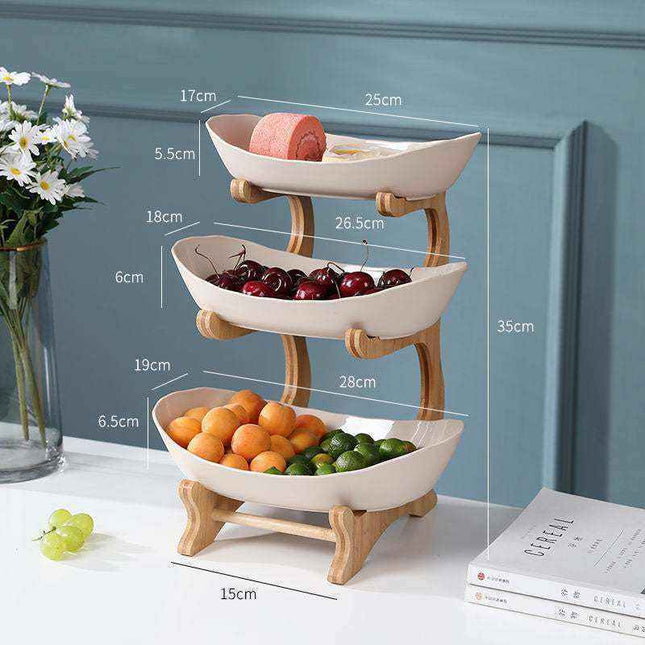 Multi-layer fruit rack in beige plastic with two layers displaying assorted fresh fruits on a countertop