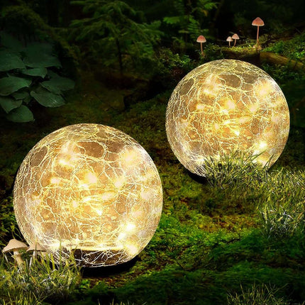 Solar crackle ball light glowing warmly in garden at night with solar panel and LED copper wire design